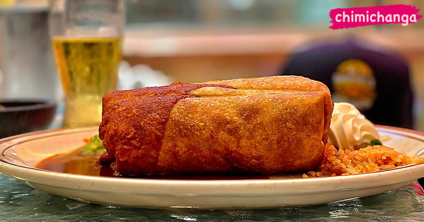 A crisp, golden chimichanga served with rice and sour cream. The image reads "Chimichanga."