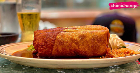 A crisp, golden chimichanga served with rice and sour cream. The image reads "Chimichanga."