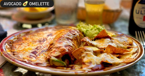 An avocado-filled omelette topped with melted cheese, with beans, guacamole and cheese-covered tortilla chips. The image reads "Avocado omelette."