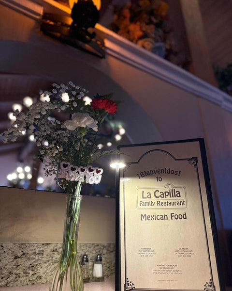 Red and white roses beside a La Capilla Family Restaurant menu reading "¡Bienvenidos!" and "Mexican Food."