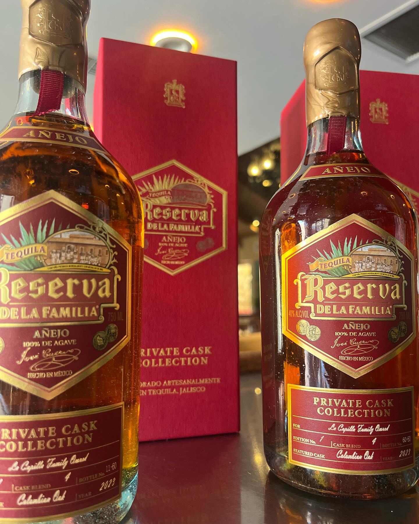 Two bottles and red presentation boxes of Reserva de la Familia añejo tequila, labeled "Private Cask Collection."